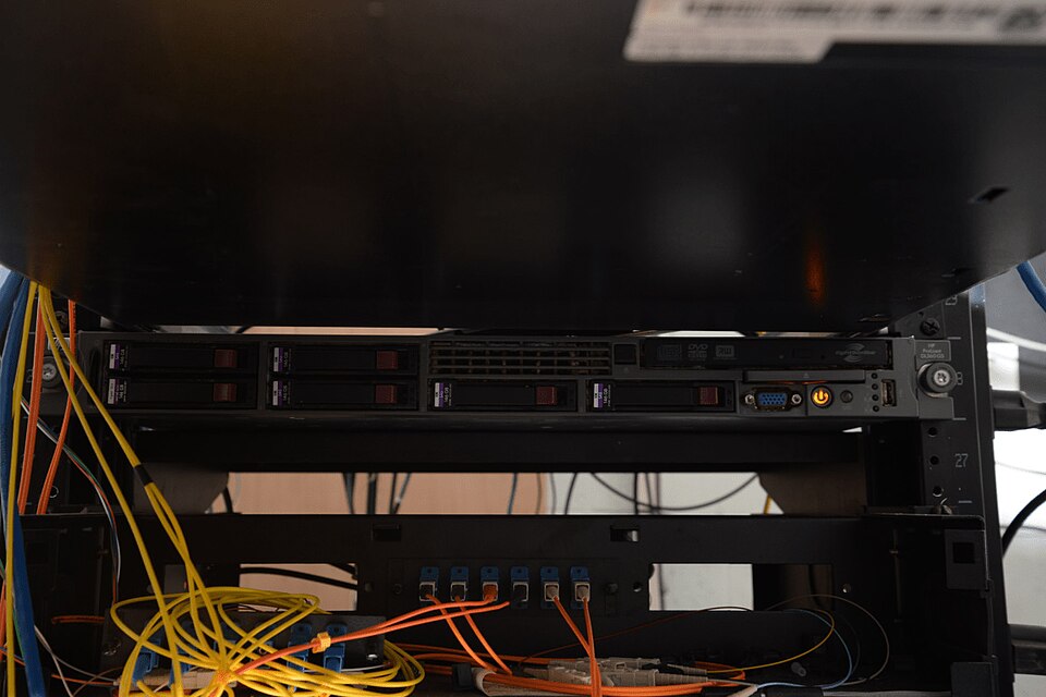 Dense server rack filled with hard drives, network switches, and connected data cables
