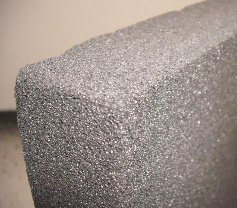 Close photograph of a porous dark gray cellular foam-glass block