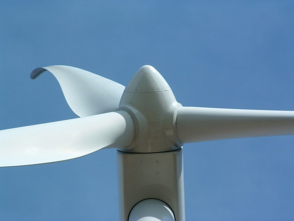 Close view looking upward at the nacelle and blades of a large wind turbine