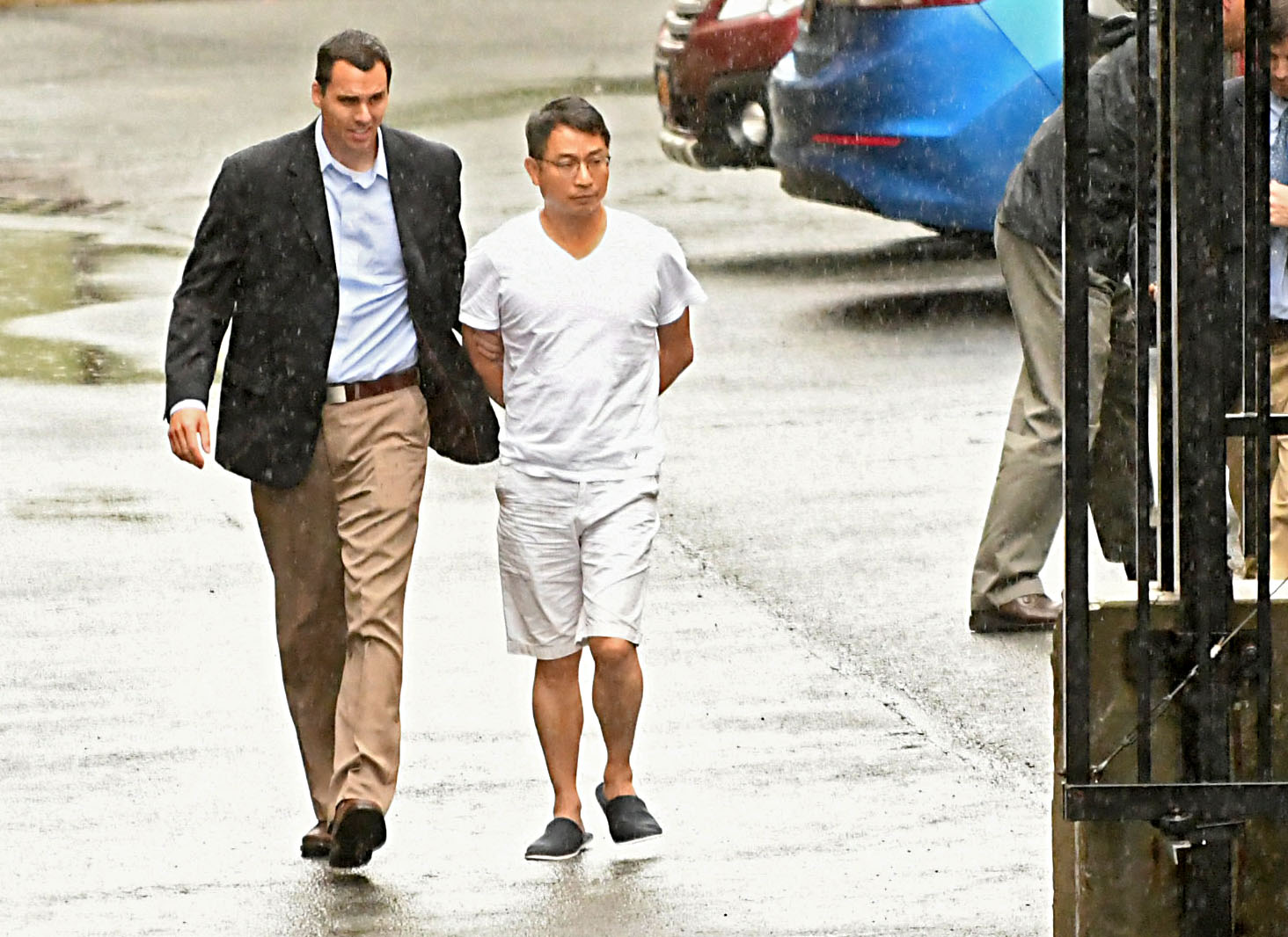 Xiaoqing Zheng walks beside a law-enforcement officer outside a federal courthouse