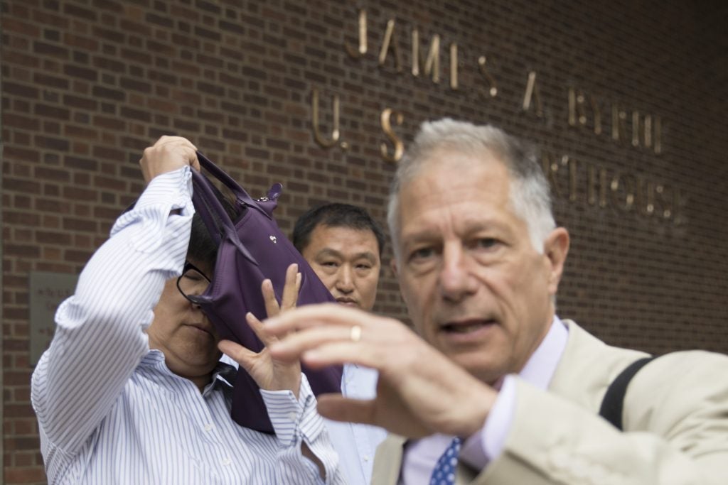 Yu Xue shielding part of her face with a handbag while leaving federal court beside her attorney